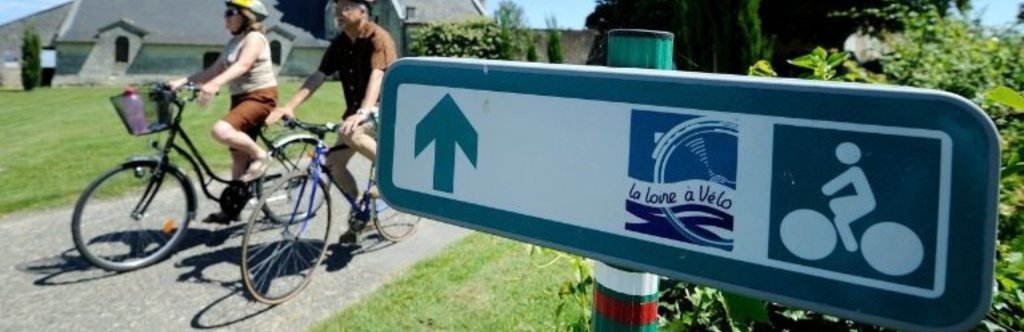 people riding bikes in the loire vally by a sign with a loire valley sticker on it